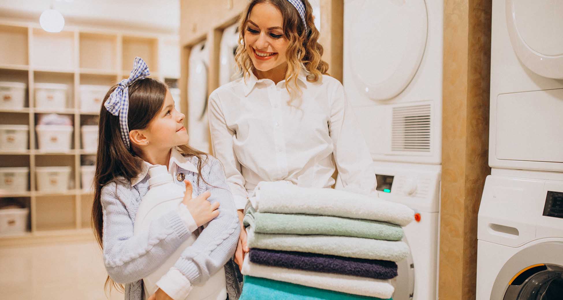 Mother with daughter doing laundry at self serviece laundrette